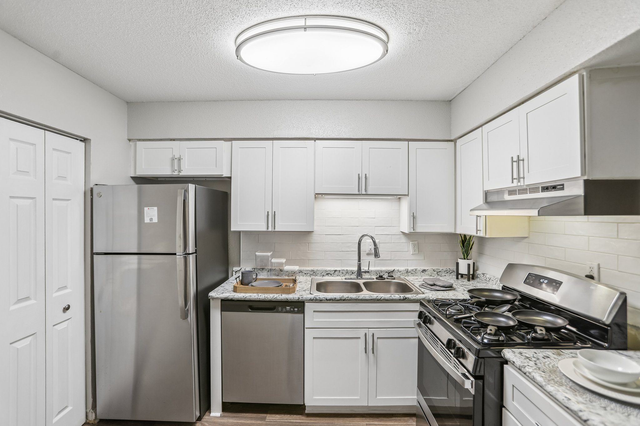 A kitchen with a refrigerator, stove, and sink.